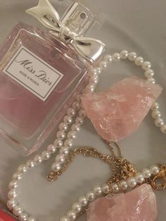 a bottle of perfume sitting on top of a table next to pearls and a necklace