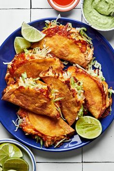 mexican food on a blue plate with limes and guacamole