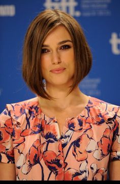 a close up of a person wearing a flowered dress and smiling at the camera