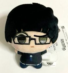 a black haired stuffed animal with glasses on it's head and hair is sitting next to a tag