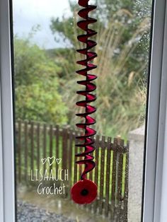 a close up of a window with a red flower on the glass and a wooden fence in the background