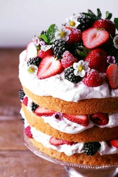 a layered cake with strawberries and blackberries on top