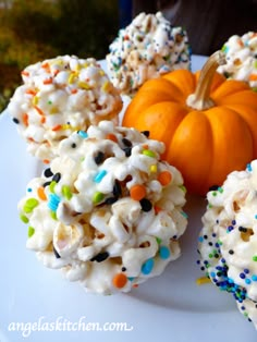 there are many treats on the plate with sprinkles and pumpkin in the background