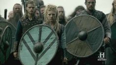 a group of people standing next to each other with shields and swords in their hands