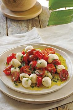 a white plate topped with sliced tomatoes and mozzarella