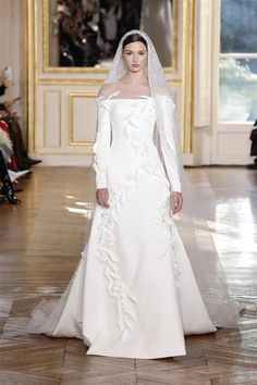 a woman in a white wedding dress with a veil on her head and long sleeves