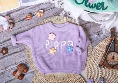 a purple sweater with the word pippa written on it next to some other items