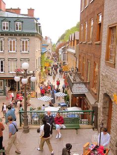 people are walking down the street in an old town with stone buildings and green railings