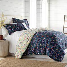 a bed with blue and white comforters on top of it in a room next to a window