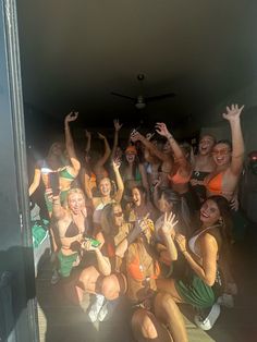 a group of women sitting on the floor in front of a door with their hands up