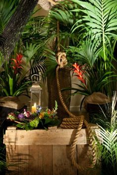 an image of a statue in the middle of some plants and flowers on top of a wooden box