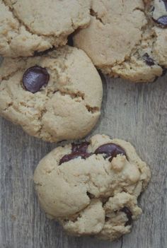 four cookies with chocolate chips on a wooden surface