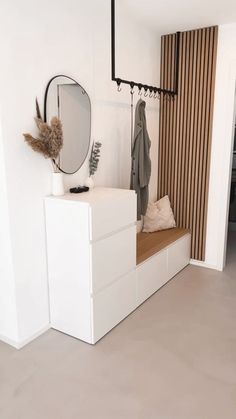 a room with a bench, mirror and coat rack