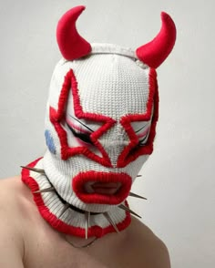 a man wearing a red and white mask with spikes on his head, nose and mouth