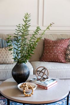 a living room with a couch, coffee table and vase on the floor next to it