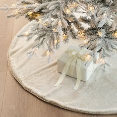 a white present box sitting on top of a rug next to a christmas tree with lights