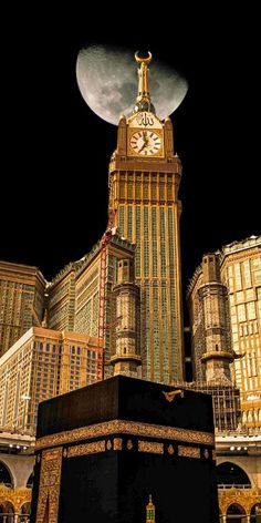 a large building with a clock on it's side in front of the moon