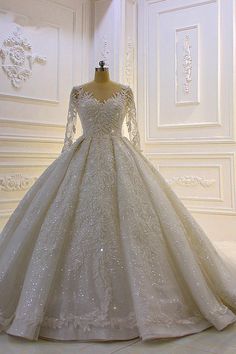 a white wedding dress with long sleeves and beadings on the skirt is displayed