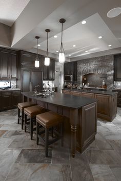 a large kitchen with dark wood cabinets and counter tops, along with bar stools