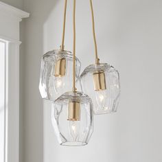 three clear glass lights hanging from a ceiling fixture in a room with white walls and windows