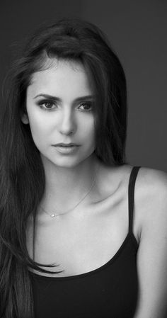 a black and white photo of a woman with long dark hair wearing a tank top