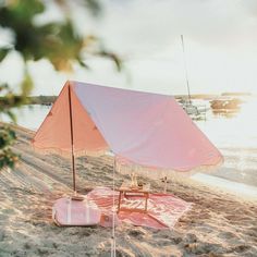 an umbrella and table on the beach with water in the background