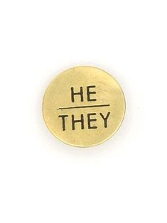 a gold pin with the words he they on it