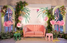 a living room decorated in pink and green with flamingos on the wall, couches and tables