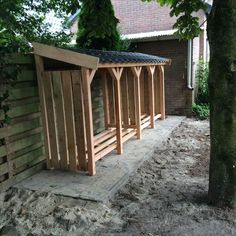 a small wooden shelter sitting next to a tree