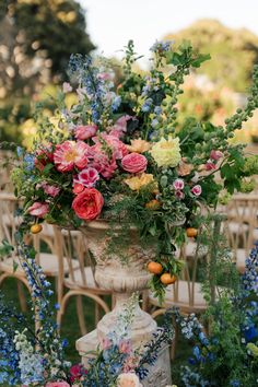 a vase filled with lots of flowers sitting on top of a table next to chairs