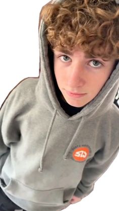 a boy with curly hair wearing a gray hoodie