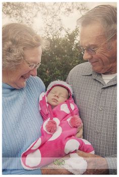 an older man and woman holding a baby