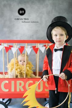 a little boy in a circus outfit standing next to a wagon with a lion on it