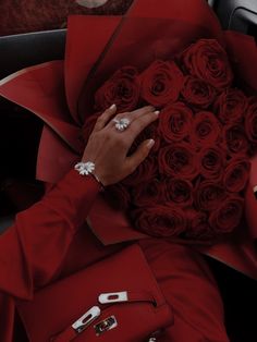 a woman is holding a bouquet of red roses in her hand while sitting in a car