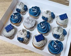 twelve cupcakes with blue and white frosting in a box