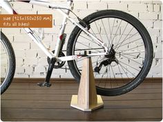 a white bicycle is on display in front of a brick wall and wooden flooring