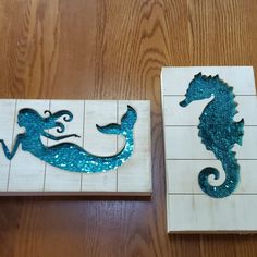 two pieces of wood with seahorses on them sitting next to each other in the shape of tiles