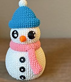 a crocheted snowman with a blue hat and scarf on it's head