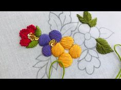 three different colored flowers sitting on top of a white table cloth with green and yellow thread