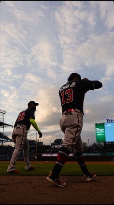 two baseball players walking on the field during a game with cloudy skies in the background