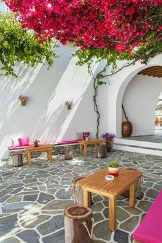 an outdoor seating area with pink flowers on the trees