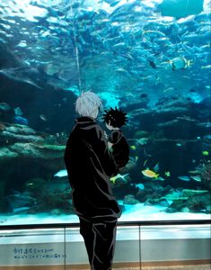 a man standing in front of an aquarium looking at fish