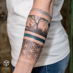 a woman's arm with a tree and mountains tattoo on the left side of her arm