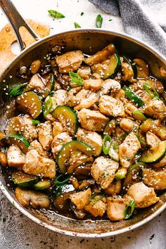 chicken and zucchini stir fry in a skillet with a spoon on the side