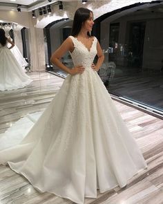 a woman standing in front of a mirror wearing a wedding dress with beading on it