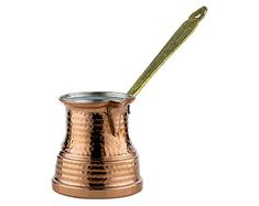 a small copper cup with a green handle and a stick sticking out of the top