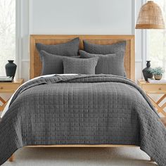 a bed with grey sheets and pillows in a room