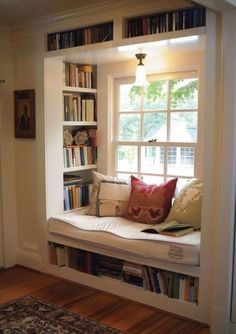 a window seat in the corner of a room with bookshelves on either side