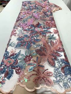 a woman is standing next to a table covered in sequins and lace fabric