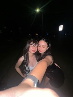 two women taking a selfie in the dark with their arms around each other,